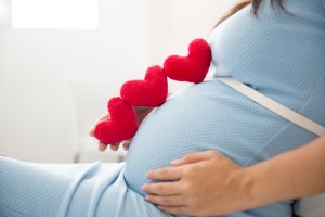 A portrait of an Asian young pregnant woman put heart shape accessories in her tummy