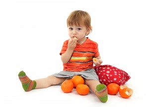 cute little boy eating tangerines, isolated on white